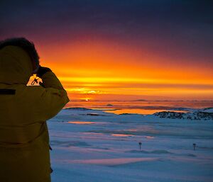 Red and yellow sunset with an expeditioner taking a picture