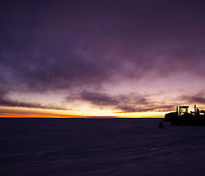 Dawn with dark purple, yellow and gold in a flat snow covered terrain