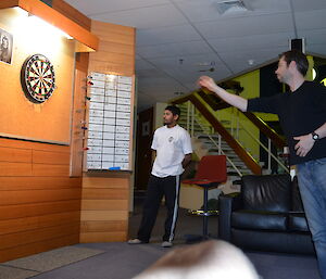 Aaron throwing darts while Abrar watches