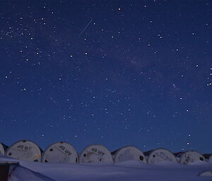 Snow covered barrels with a starry night sky