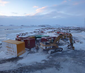 View from the lower fuel farm of the frozen sea ice in the background and shipping crates and excavator in the foreground