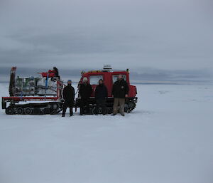 Snowy flat terrain with the Wilkes party standing in front of a red Hagg