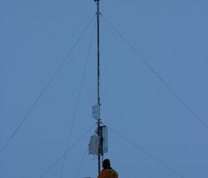 Leon sitting under the AWS taking readings from the AWS in a flat snowy terrain