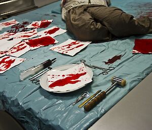 Table setting with fake blood stains and medical utensils