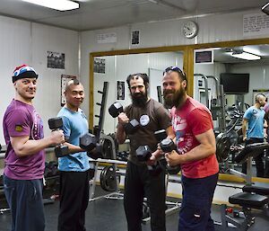 P90X group picture in the gym holding weights and flexing their muscles