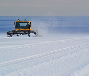 A groomer in the distance in a flat and snowy terrain