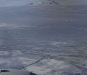 Pictures of a snow covered volcano with low cloud below its peak