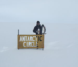 Wide angle shot of Gavin standing behind the Arctic Circle sign