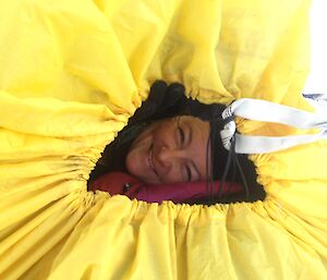 Linda in a yellow Bivvy bag with her head sticking out looking at the camera