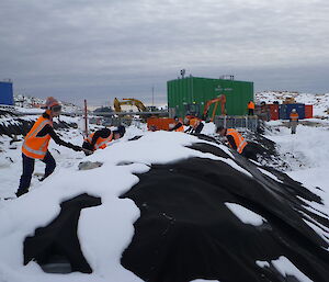 Helpers removing snow from the biopiles with shovels.