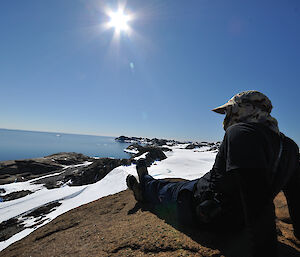 Stu sitting on the rocks and staring out at the water