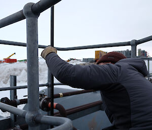 An expeditioners checks a tank level from above with a dip stick