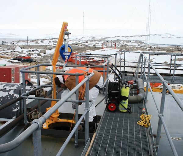 An expeditioner monitors the fuel tank cleaning from above the tank