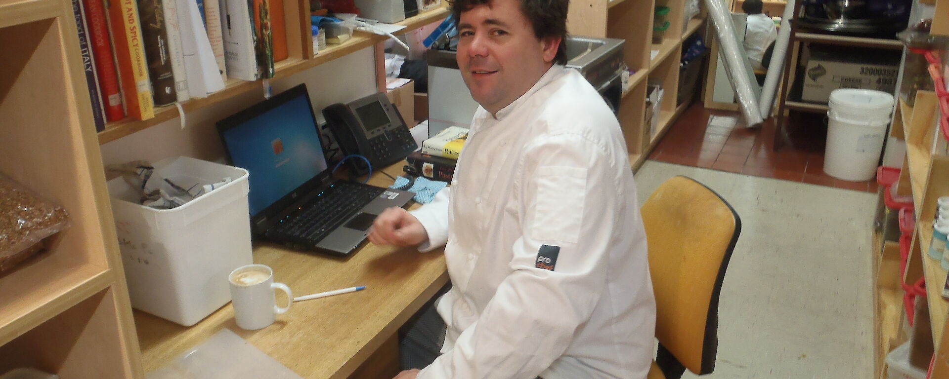 Eddie, the wintering Casey chef, sits on a stool in uniform