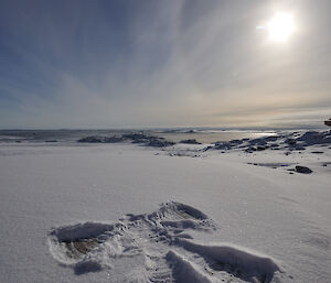 Pattern formed in the snow by lying down and spreading arms and feet — resembles an angel