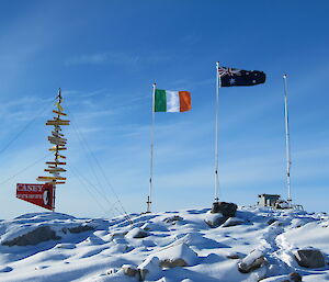 A view of the Casey signpost, the Irish Flag, and the Australian flag flying at Casey on St Patrick’s Day