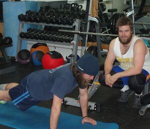 Expeditioner Steve watches over Cary as he trains in the gym at Casey station, Antarctica