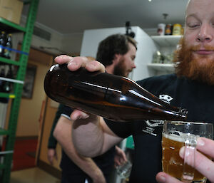 An expeditioner tasting a home brew beer at Casey station, Antarctica