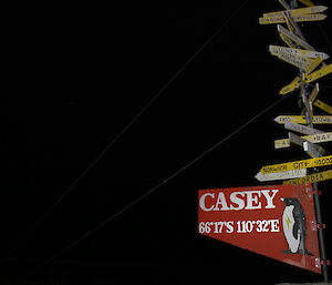 The Casey sign at night — a wooden sign indicating Casey station but also on the pole above are smaller signs indicating the directions of other places from Casey