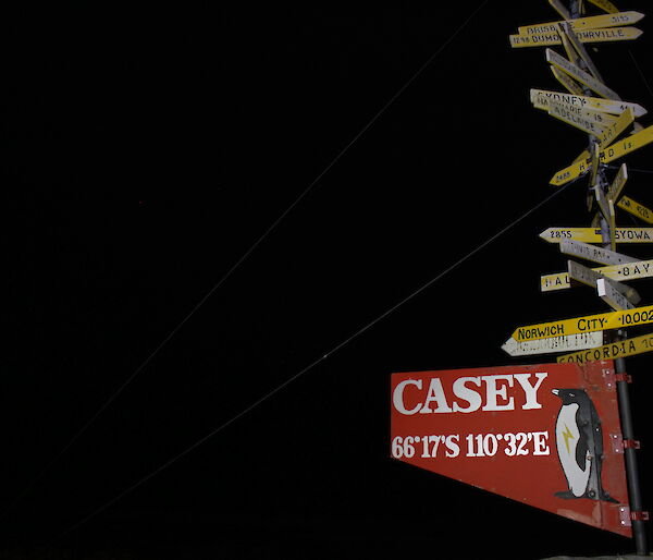 The Casey sign at night — a wooden sign indicating Casey station but also on the pole above are smaller signs indicating the directions of other places from Casey