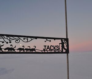 The sign marking the turn off to Jacks hut at Casey — with moon and pink sunset hues.
