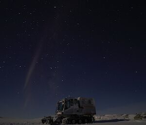 Aurora australis glowing in the sky over the trooper tracked vehicle, at Robbos hut