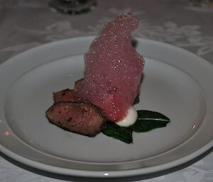Entree sized dish with fillet of lamb with goat cheese ravioles and beet foam