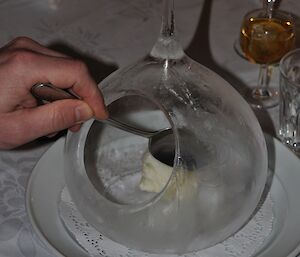 Expeditioner inserts a spoon into a large, teardrop shaped, thin ice ‘igloo’ containing lemon sherbet sorbet — photo taken from above