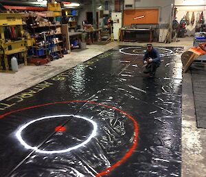 Black polythene sheet lain out in the Workshop ready for curling game — part of the Midwinter games at Casey 2014