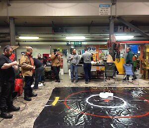 Casey expeditioners gather in the Workshop to watch the curling game — part of the 2014 Midwinter celebrations