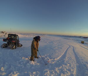 An expeditioner lines up a golf shot in Antarctica, surrounded by ice