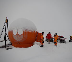 Kenny emergency hut and expeditioners, on a snowy day.