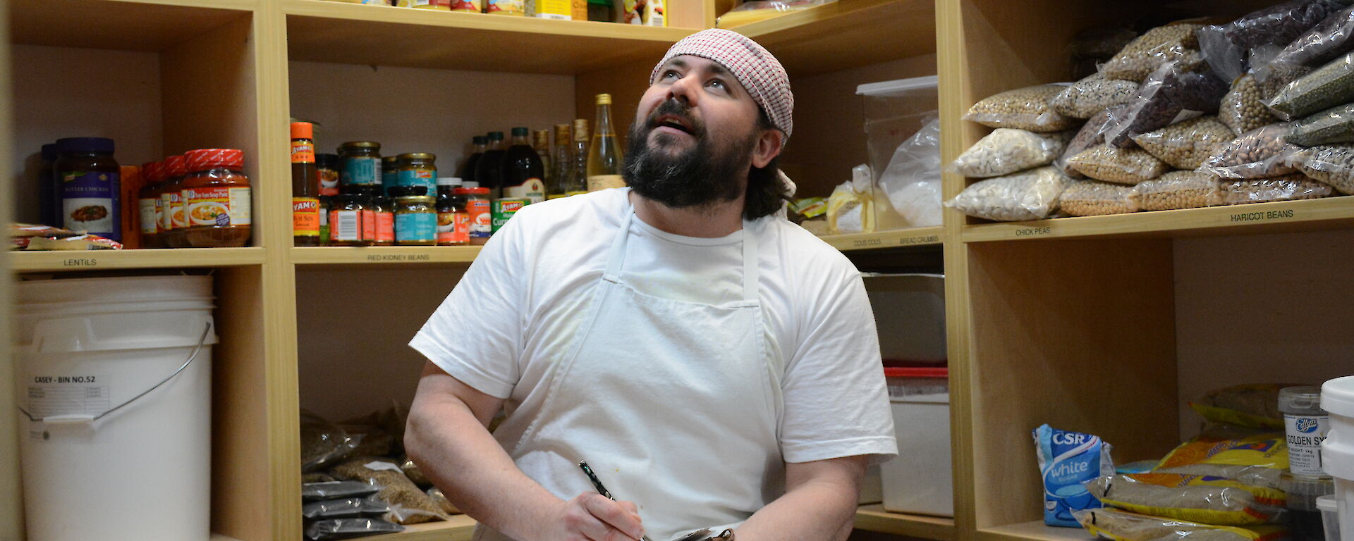 An expeditioner writing poetry in the food pantry at Casey station, Antarctica.