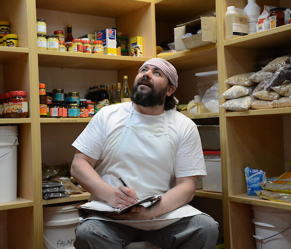 An expeditioner writing poetry in the food pantry at Casey station, Antarctica.
