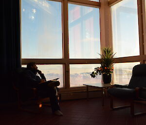 An expeditioner looks to the horizon, through the wallow windows at Casey station, Antarctica.