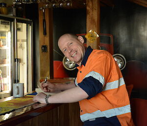 An expeditioner at the bar at Casey station, writing poetry.