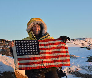 Station leader Ali holds up a small American flag from the Peterson Island memorial