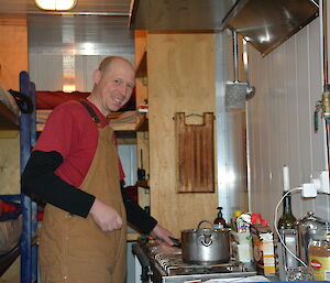 An expeditioner cooks up a storm with a single saucepan and a small kitchen stove in a remote Antarctic field hut.