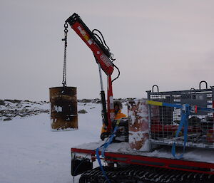 An expeditioner loads a 44 gallon drum onto the back of a Hägglunds vehicle at Brownings hut.