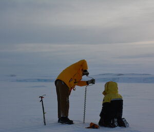 Expeditioners drill and test the sea ice with a hand auger prior to travel across it.