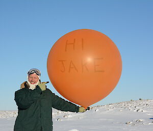 An expeditioner about to launch a weather balloon with a personalised message written on it