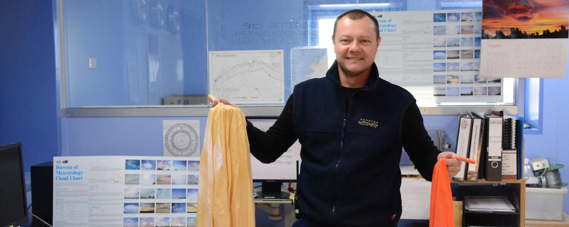 An expeditioner in the operations building at Casey, receiving an meteorological prize pack.