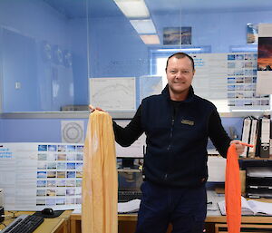 An expeditioner in the operations building at Casey, receiving an meteorological prize pack.