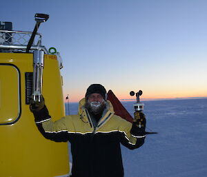 A meteorologist performs improvised weather readings using portable equipment, alongside a Hägglunds