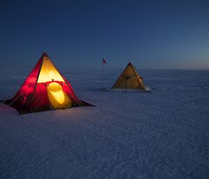 Polar pyramid tents lit from inside at dusk, at the Antarctic circle