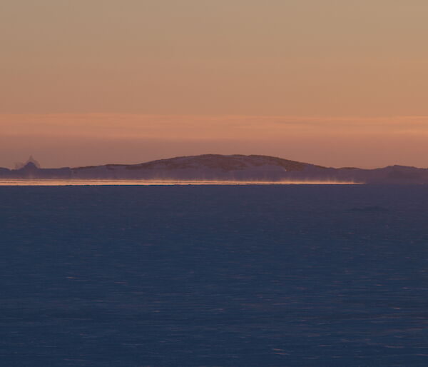 Steam rising above the almost frozen ocean at sunset