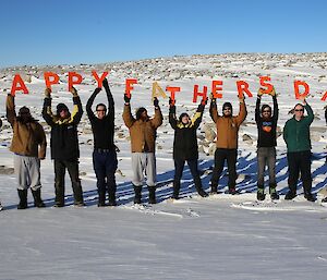 Casey expeditioners hold up letters spelling Happy Father’s Day on 7th September 2014