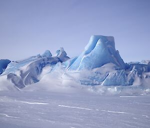 A flat topped blue iceberg pokes up from the white frozen ocean, enroute to Brownings hut