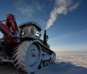 A Challenger tractor warms up with fog bellowing from the exhaust, on a cold morning in Antarctica