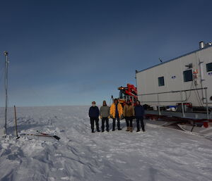 The five expeditioners on the traverse line up for a group photo in front of the traverse van, at Law Dome, Antarctica